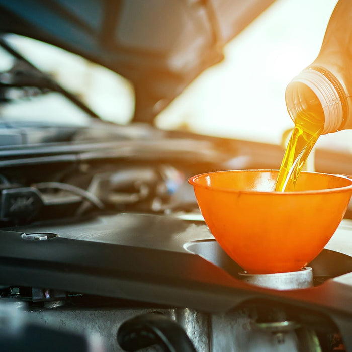 Car undergoing oil change maintenance with mechanic in workshop